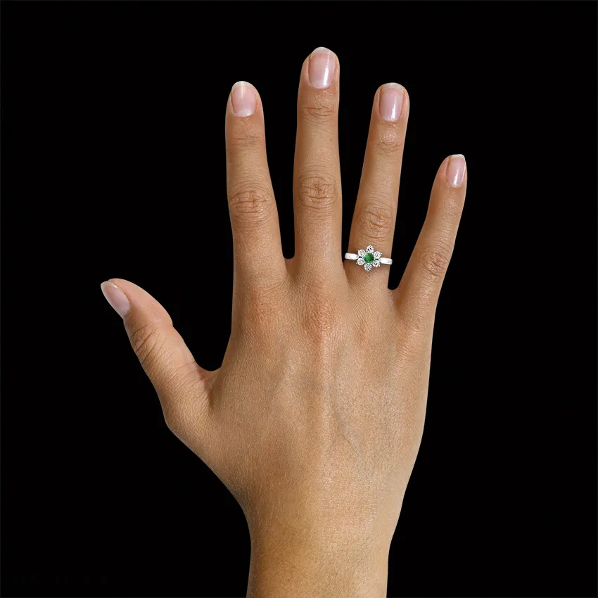Anillo flor en oro blanco con esmeralda redonda y diamantes en los lados 